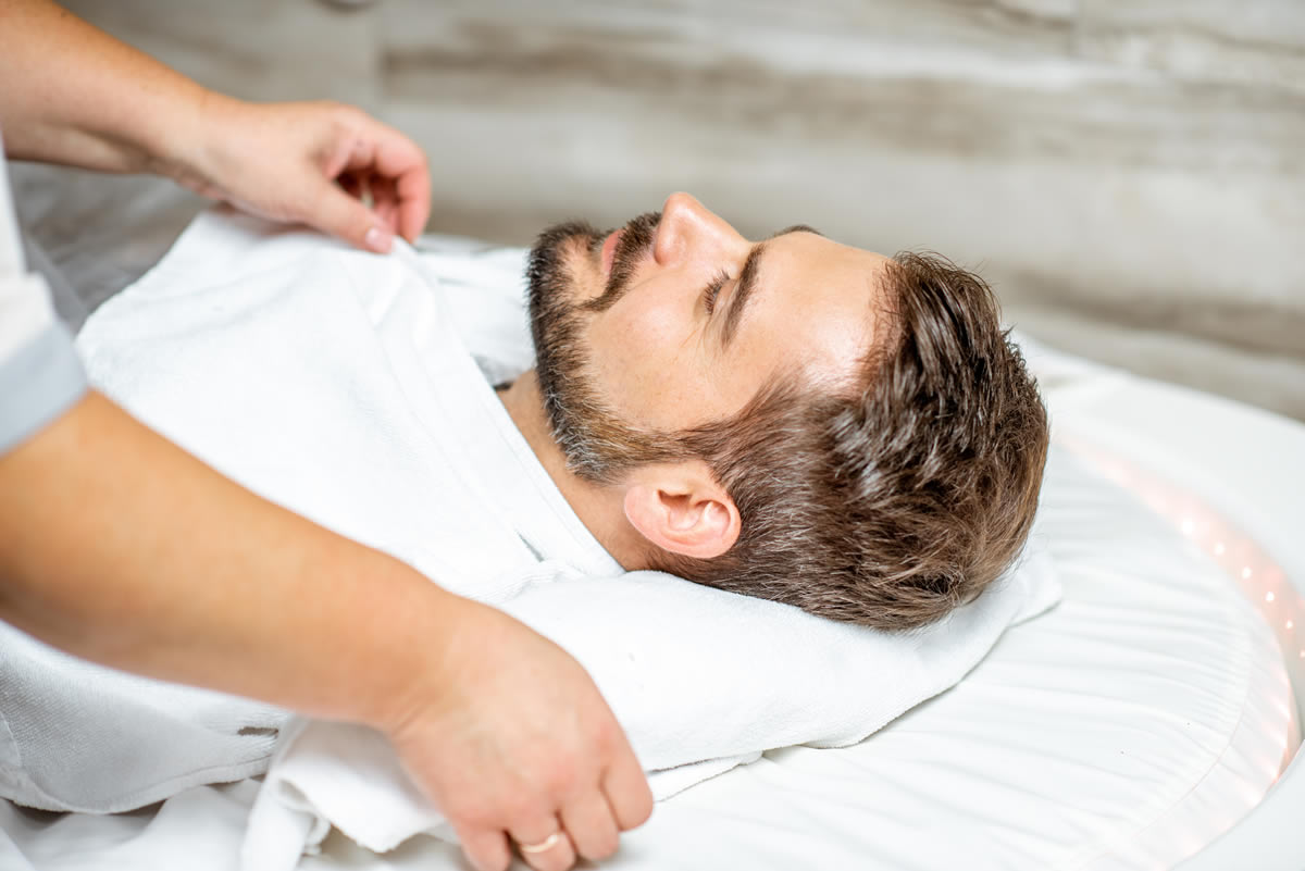 hombre tumbado mientras le hacen un masaje